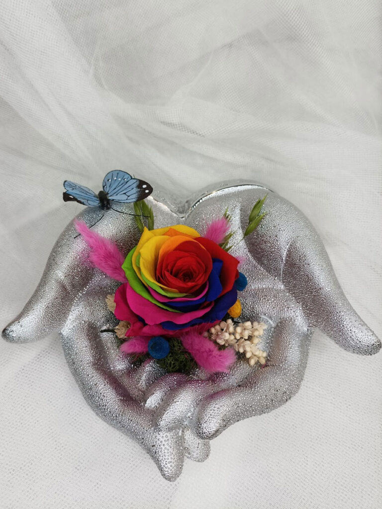 Manos sinceras, figura con forma de manos unidas con una rosa eterna
